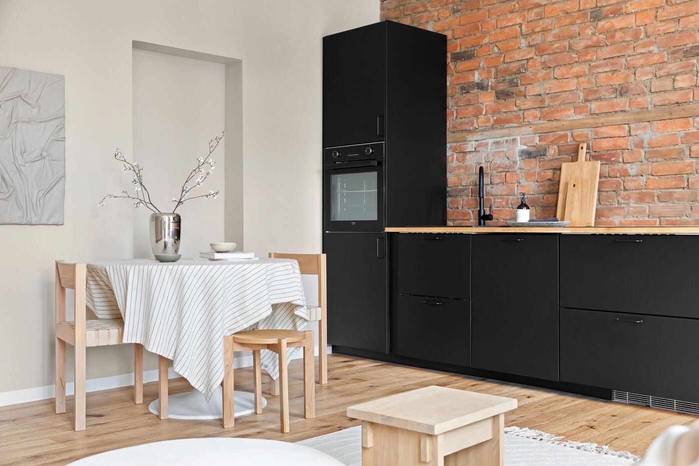 Comedor con pared de ladrillo visto y cocina negra